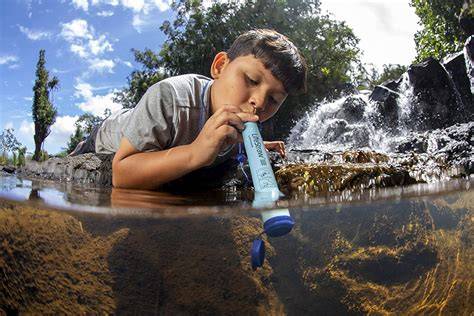 Excursionista usando filtro LifeStraw en río