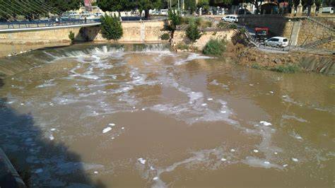 Espumas blancas en río junto depuradora